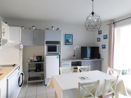 uma cozinha com uma mesa e um frigorífico branco em TY MAGARI em Plougonvelin