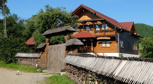 a large wooden house with a balcony on top of it at Pensiunea Ardelean in Vadu Izei