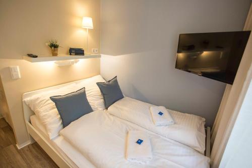 a small room with a white bed with blue pillows at GuestHouse Köhn51, zentral gelegene, stilvoll eingerichtete Zimmer mit eigener Teeküche in Nürnberg