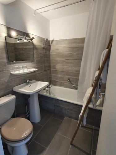 a bathroom with a sink and a toilet and a bath tub at HOTEL DU GRAND LAC in Laffrey