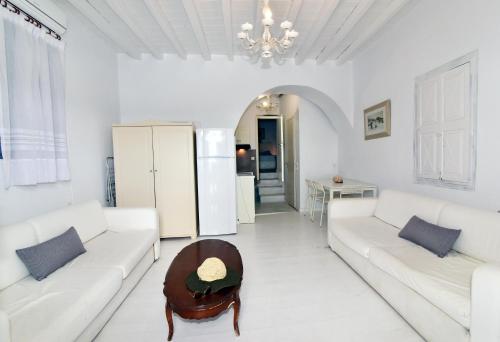 una sala de estar con muebles blancos y una lámpara de araña. en Thomas Traditional House in Chora, en Amorgós