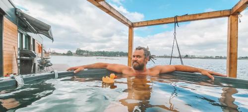 a man in a hot tub on a boat on the water at Costa del Kryspi Całoroczne Domy na Wodzie in Cholerzyn