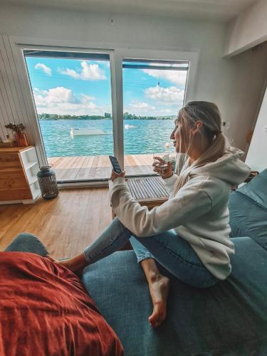 a woman sitting on a couch looking at her cell phone at Costa del Kryspi Całoroczne Domy na Wodzie in Cholerzyn