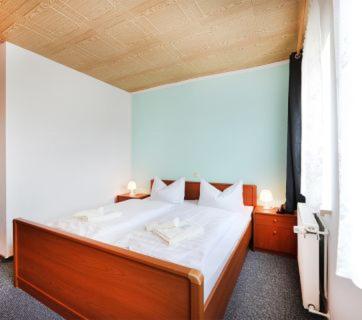a bedroom with a large bed with a wooden headboard at Hotel "Zum Einsiedler" in Deutschneudorf