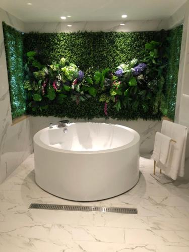 a bathroom with a white tub with a green wall with flowers at Mumu Motel in Guishan