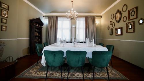 a dining room with a white table and green chairs at Cincis by the Lake in Cinciş