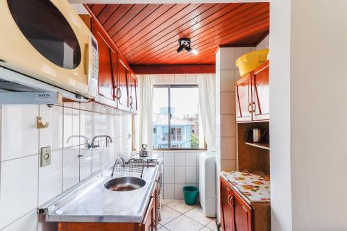 una pequeña cocina con fregadero y ventana en Vista para o Mar no Sul de Ingleses - HK04F, en Florianópolis