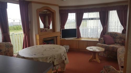 a living room with a table and a tv in a room at The Chase Ingoldmells in Ingoldmells