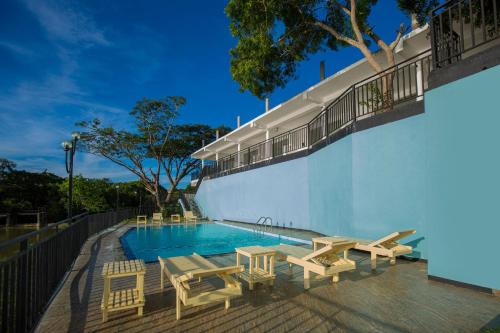 una piscina con mesas y sillas junto a un edificio en Olu villa Resort en Tissamaharama