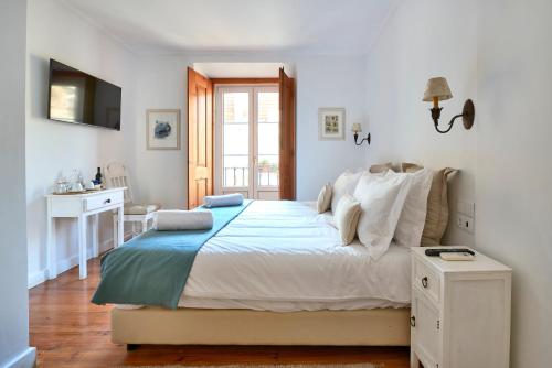 a bedroom with a white bed and white walls at Casa do Mercado Lisboa in Lisbon