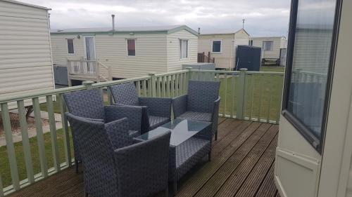 a balcony with chairs and a glass table on a deck at The Chase Ingoldmells in Ingoldmells