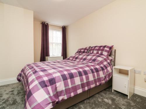 1 dormitorio con 1 cama con manta de cuadros púrpura en 1 Tregonwell Court, en Minehead