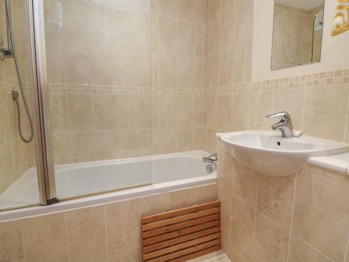 a bathroom with a sink and a shower and a tub at 1 Tregonwell Court in Minehead