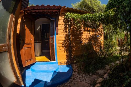 una pequeña casa con una puerta abierta en un patio en Shanti - Hospedaria na Vila de São Jorge en Sao Jorge