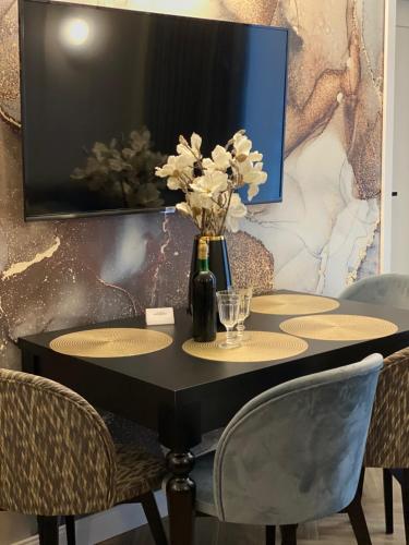 a table with chairs and a vase with flowers on it at Family & Business Sauna Tężnia Apartments No12 Leśny nad Zalewem Cedzyna - 1 Bedroom with Private Sauna, Bath with Hydromassage , Terrace, Parking, Catering Options in Kielce