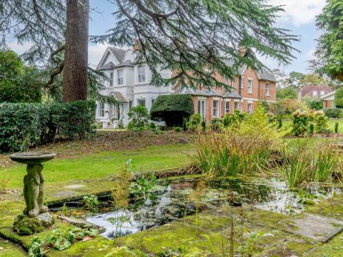 a garden with a pond in front of a house at Claridge House in Lingfield