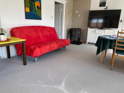 a red couch in a living room with a television at Stor lys lejlighed på Nordmors in Sejerslev