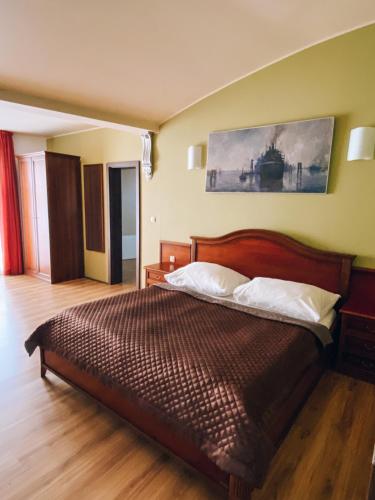 a bedroom with a bed and a painting on the wall at Riverside Apartments Thalia in Karlovy Vary