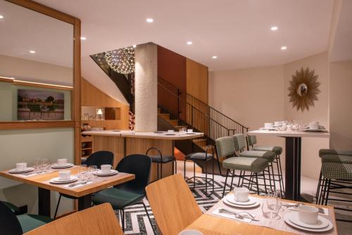 a restaurant with tables and chairs and a staircase at Hotel Yllen Eiffel in Paris