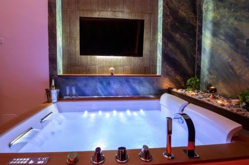 a bathroom with a bath tub with a tv at Pompei Luxury Rooms in Pompei