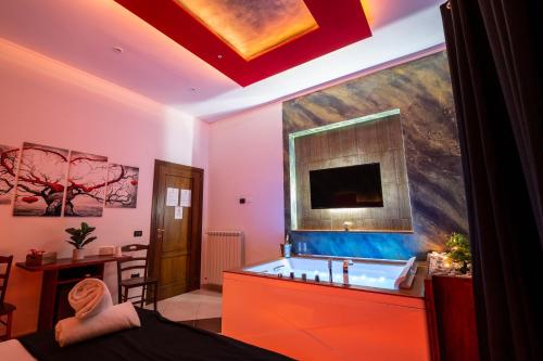 a bathroom with a tub and a tv on the wall at Pompei Luxury Rooms in Pompei