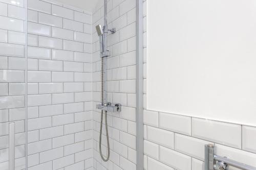 a shower with a hose in a white tiled bathroom at Percy Place - Modern 1 bedroom ground floor apartment in central Southsea, Portsmouth in Southsea
