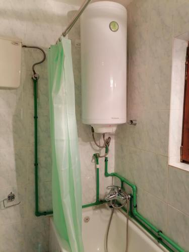 a bath tub with a green shower curtain in a bathroom at Divčibarski M.S.A. kutak in Divčibare