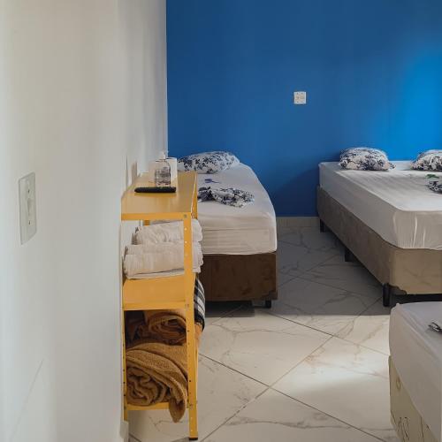 a room with two beds and a shelf with towels at Pousada Maria Maria Próximo ao Santuário Nacional in Aparecida