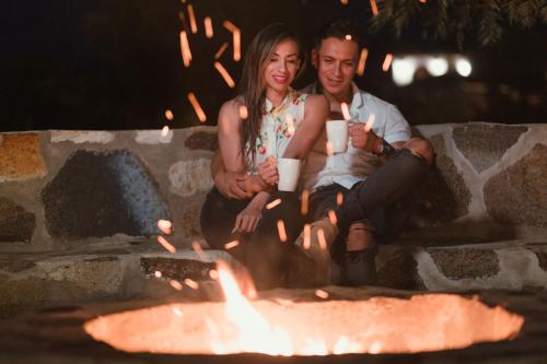 a man and a woman sitting next to a fire at Hacienda Los Olivos, Valle de Guadalupe in Rancho Grande