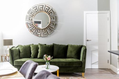 a green couch in a living room with a mirror at Elizabeth Mews - By Luxury Apartments in Cheltenham