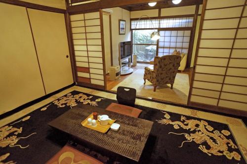 a living room with a table and a chair and a room withryu at Mujinzo in Yufuin