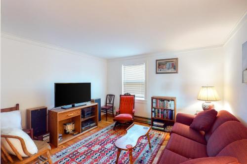 a living room with a red couch and a flat screen tv at Heluvaspot in Port Clyde