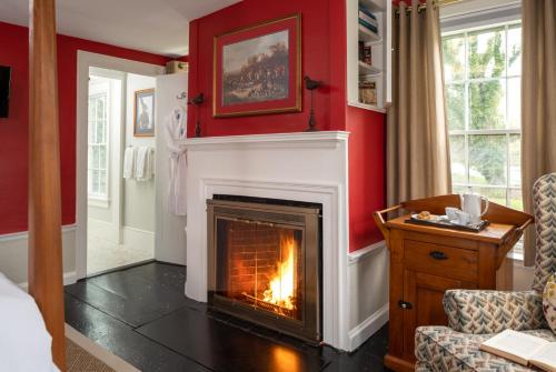 a living room with a fireplace and red walls at Candleberry Inn on Cape Cod in Brewster