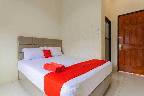 um quarto com uma cama com um cobertor vermelho em RedDoorz near Arka Sepinggan Airport em Balikpapan