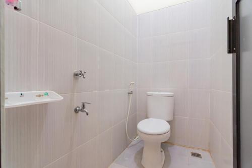 a white bathroom with a toilet and a sink at RedDoorz near Arka Sepinggan Airport Balikpapan in Balikpapan
