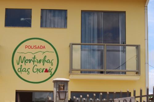上波蘇的住宿－Pousada Montanhas das Gerais，黄色的建筑,旁边标有标志