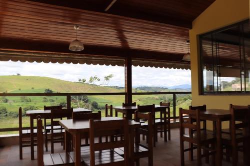 um restaurante com mesas e cadeiras e uma grande janela em Pousada Montanhas das Gerais em Pouso Alto
