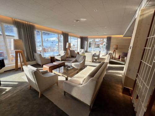 a living room with couches and chairs and windows at Le Bristol Leukerbad in Leukerbad