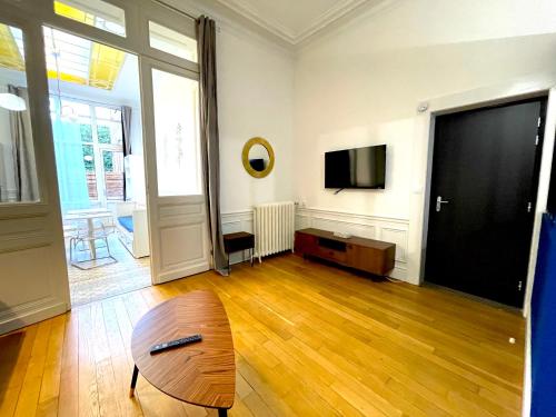 a living room with a table and a flat screen tv at Résidence Adam à part in Valenciennes