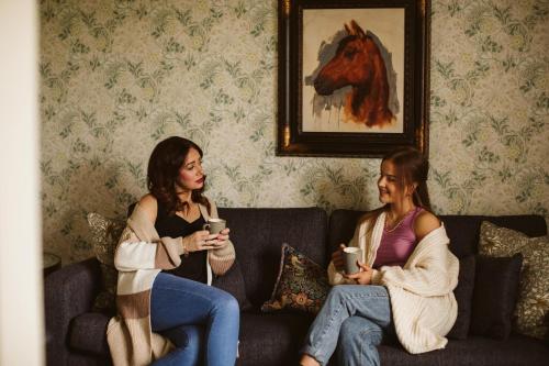 two women sitting on a couch with cups of coffee at Galgorm in Ballymena