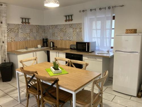 a kitchen with a wooden table with chairs and a refrigerator at La marine D'opale in Ambleteuse