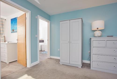 um quarto com paredes azuis e um armário branco em Treveth Lowen em Saint Minver