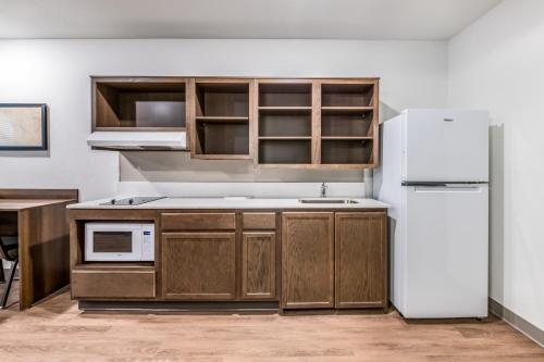a kitchen with wooden cabinets and a white refrigerator at WoodSpring Suites Tampa Airport North Veterans Expressway in Tampa