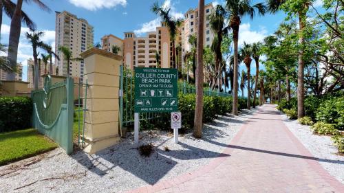 a sign on a sidewalk next to a street with palm trees at Prime Location I 2 Bed Setup Directly Across Street From South Beach Access in Henry Key