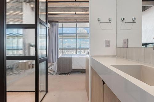 - une cuisine avec des comptoirs blancs, un lit et une fenêtre dans l'établissement Vossa Bossa Copan, à São Paulo