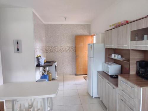 ウバトゥバにあるApartamento confortável em Marandubaのキッチン(白いテーブル、白い冷蔵庫付)