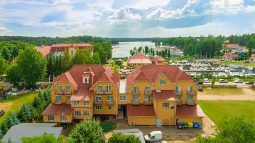 ein großes gelbes Haus mit rotem Dach in der Unterkunft Hotel Helena in Giżycko