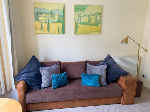a brown couch with blue pillows in a living room at Park Crescent Lodge - Quaint Victorian Home With Free Parking in York