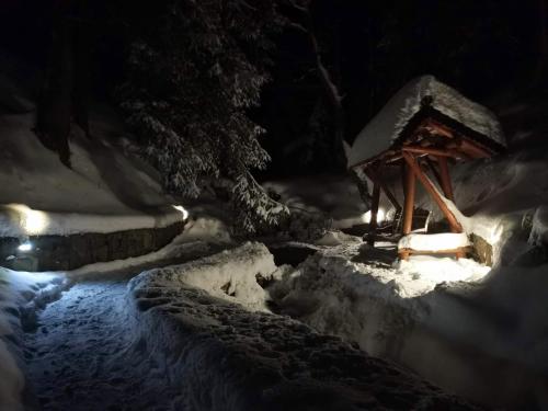 a snow covered bridge with a wooden structure next to a stream at ГІРСЬКА ХАТА in Senechiv