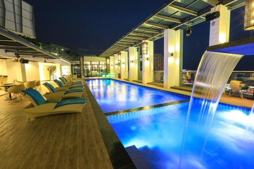 a hotel pool with chairs and a water fountain at Eco Tree Hotel, Melaka in Malacca